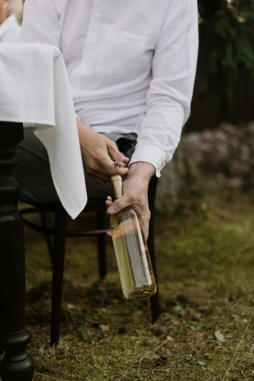 man holding a bottle of liquor outdoors sitting down