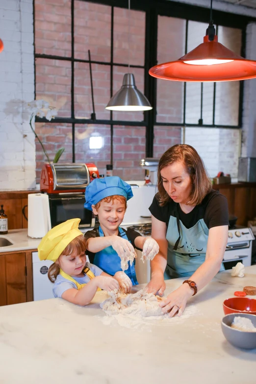 two women and three children are making cookies