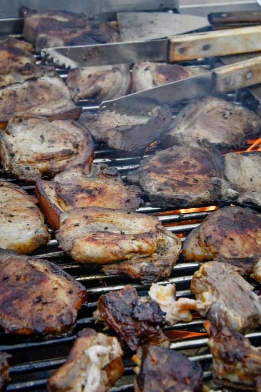 a barbecue grill with beef and steaks being cooked on the outside