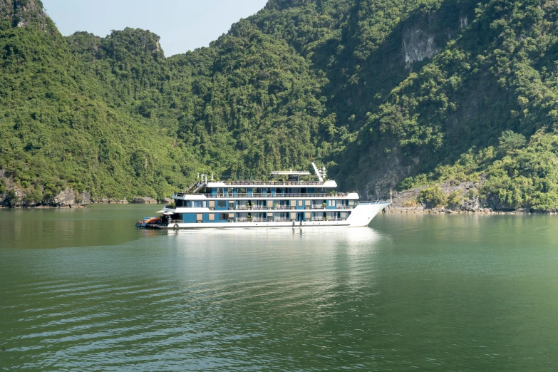 a blue and white boat floating on top of a river near mountains