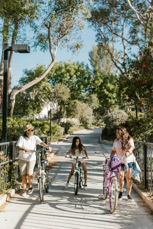 a group of young people riding bikes and walking down a street