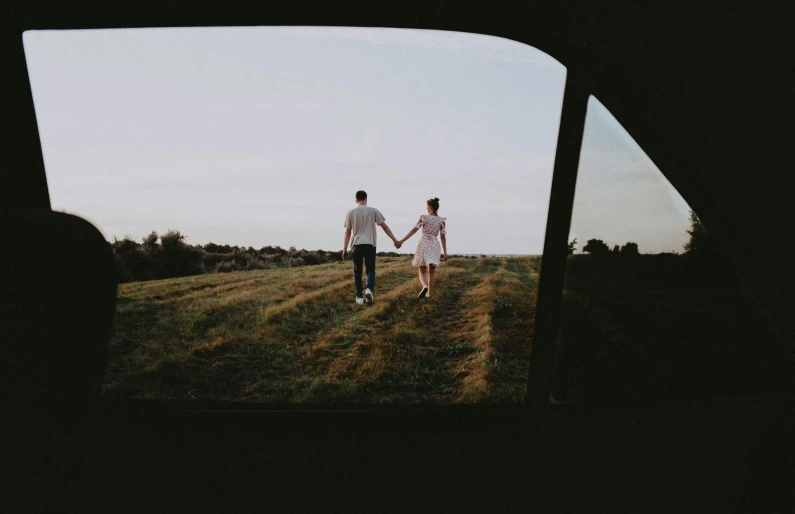 two people are walking in the grass holding hands
