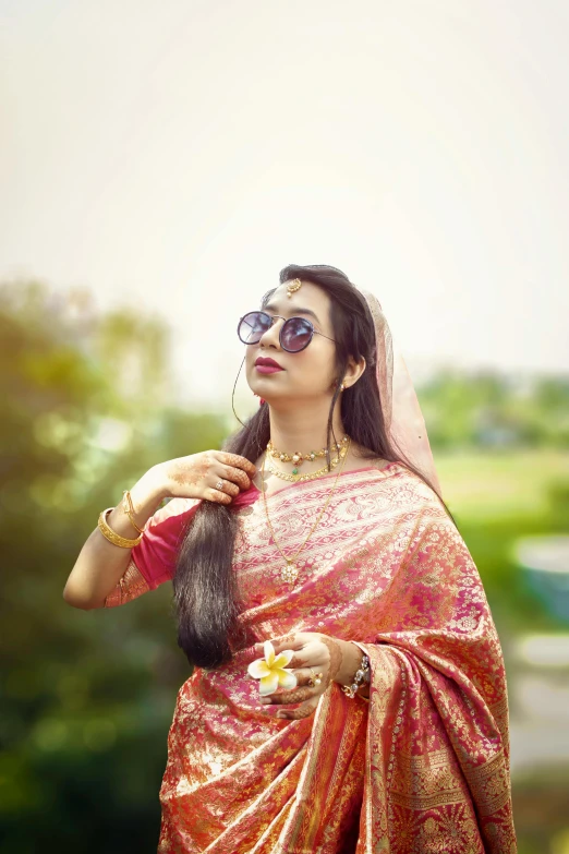 a woman in a red and gold saree is posing