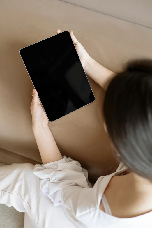 woman playing with her tablet while lying on a couch