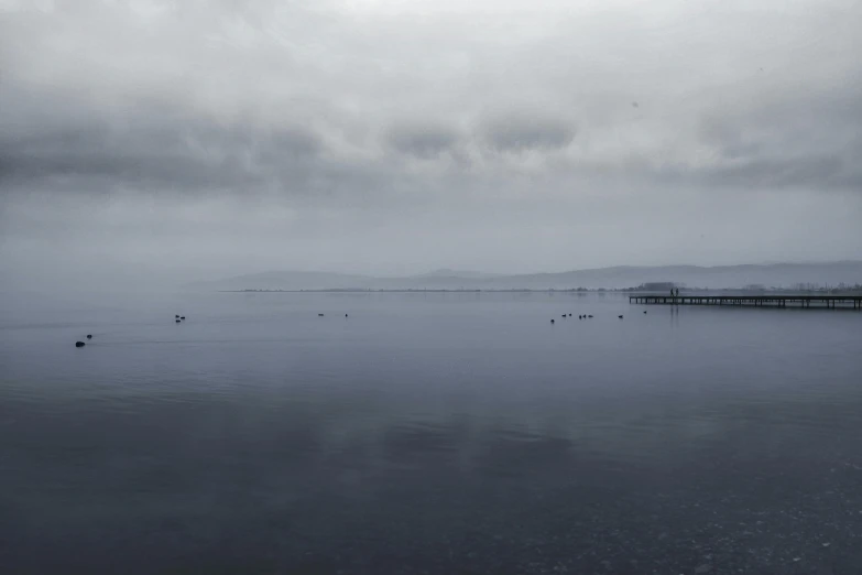 black and white pograph of ocean with foggy sky