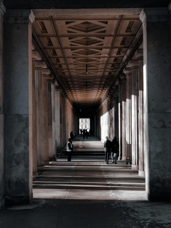 the view of several people walking through an unfinished area of cement and wooden pillars