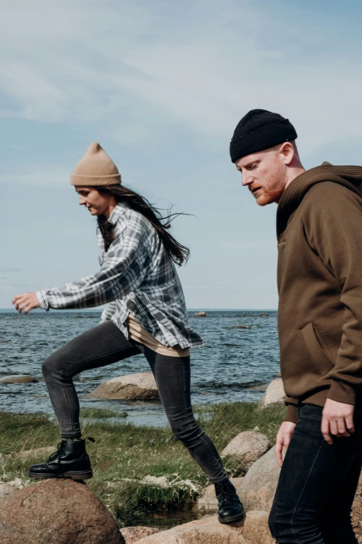 two people standing on rocks and rocks looking at the water