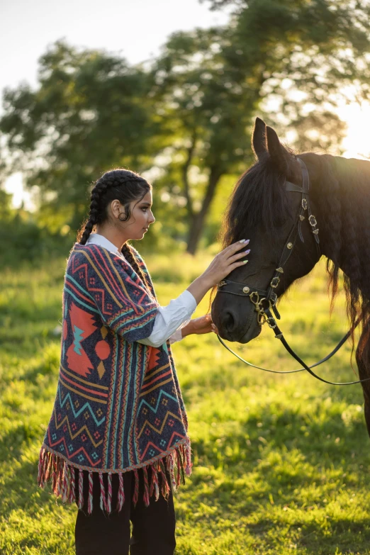 woman holding reigns as a horse grazes in the field