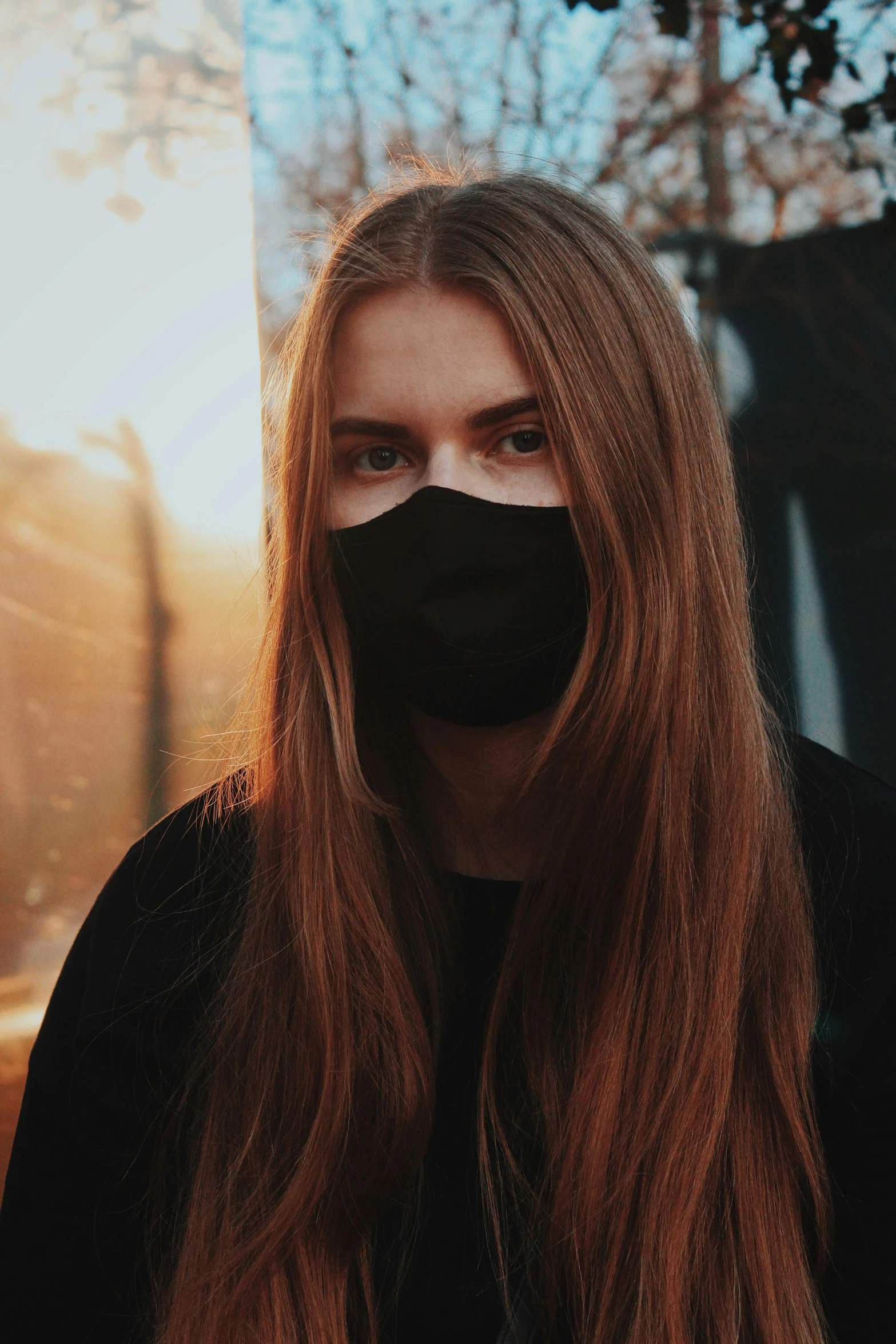 a woman with long red hair and a mask covering her face