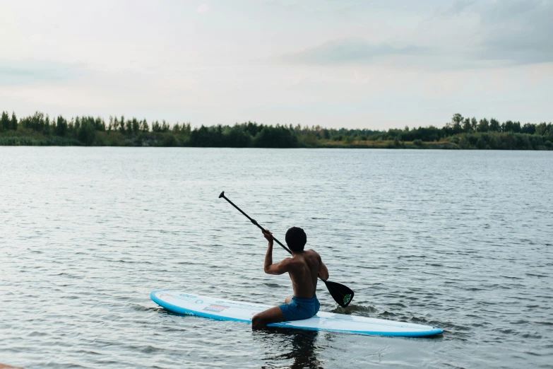 the man is sitting on his surfboard holding onto a stick