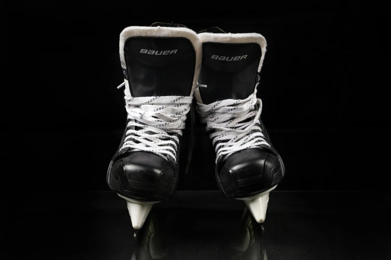 two pairs of hockey shoes in a dark room