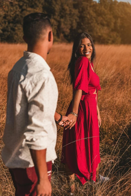 a woman and man in an open field with tall grass