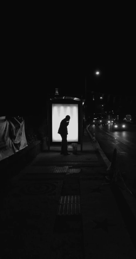 a person stands in the dark by a city bus stop