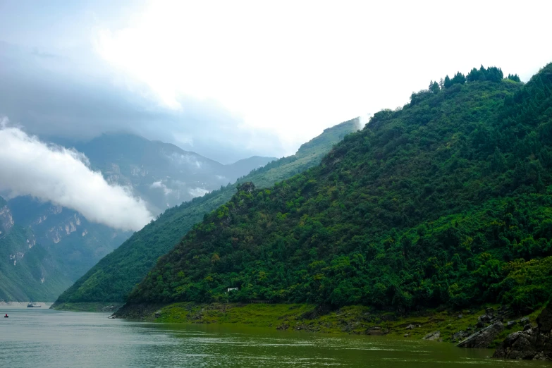 some people riding boats on a river next to a mountain