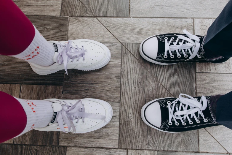 three people in pairs with different colored socks are standing on a wooden floor