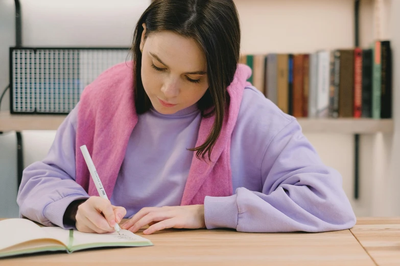 girl studying on a book at a table with an open book