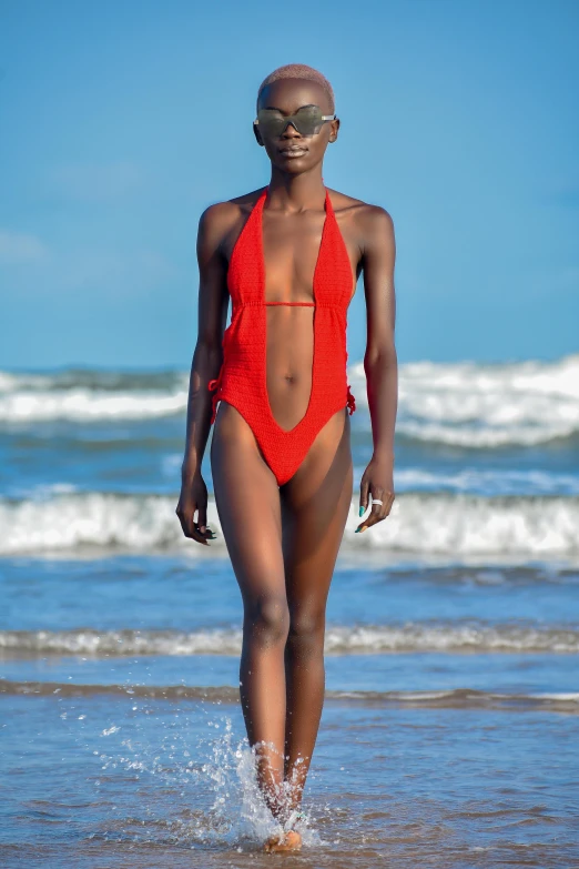 a woman walking across the beach with an alien head