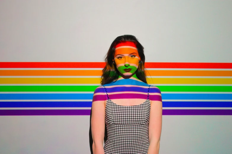 a girl in an orange, green, and blue shirt with her mouth covered in makeup