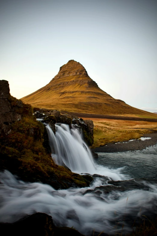 a large mountain next to a small river