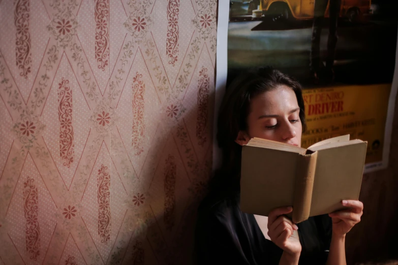 a person leaning up against a wall reading a book