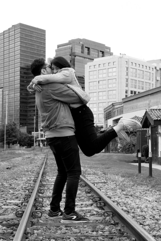 black and white po of couple hugging each other on train tracks