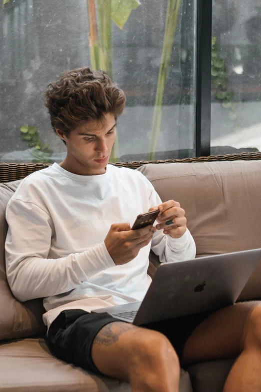 the young man is sitting down looking at his laptop