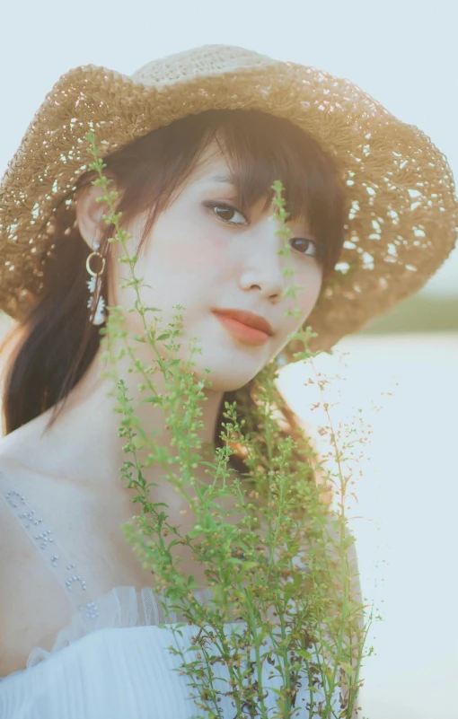 a woman wearing a straw hat while standing next to a grass field