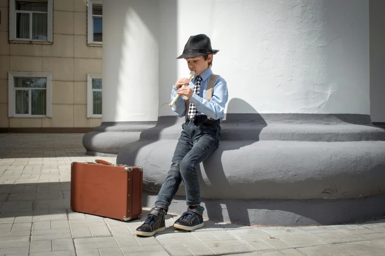 man sitting on large piece of luggage near a sculpture