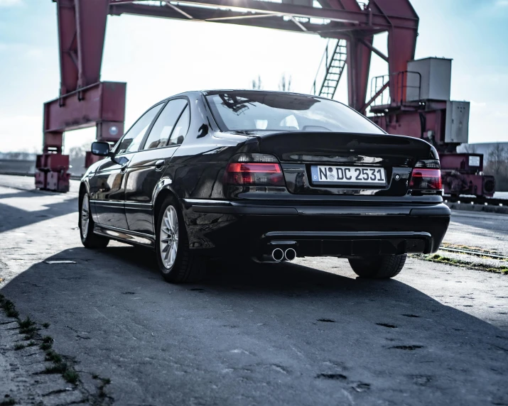 a black car is parked in the road under an overpass