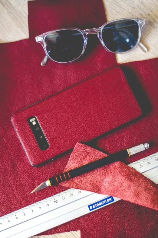 a pair of glasses, pen, ruler, sunglasses and red notebook