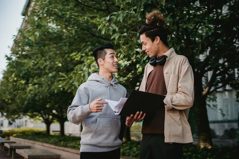 two people are standing on the sidewalk together talking