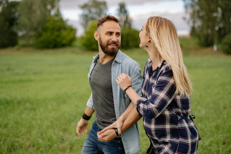 a woman in jeans walking behind a bearded man in a plaid shirt