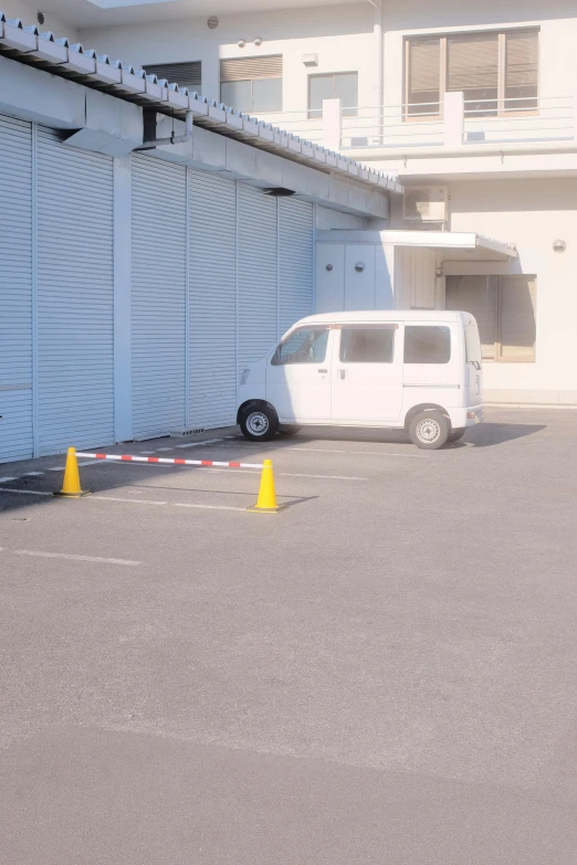 a van parked near several yellow cones in front of a building