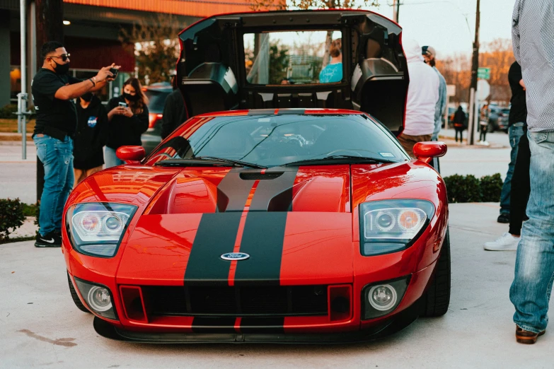 a red sports car sitting in front of people