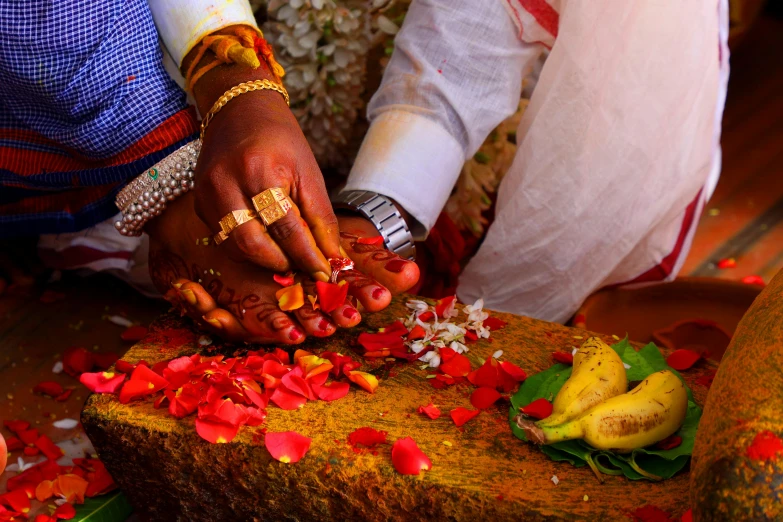 a close - up of a woman is wearing gold and has her hands covered with food, petals and petals