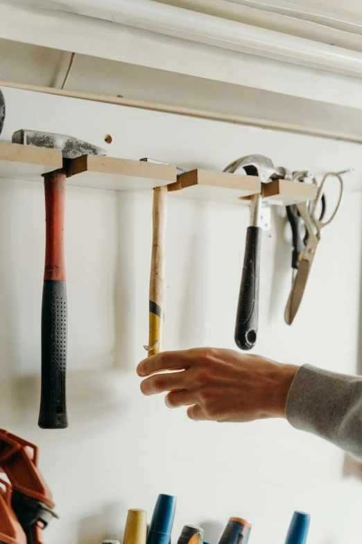 someone holds their arm and hammer as he stands by several different tools