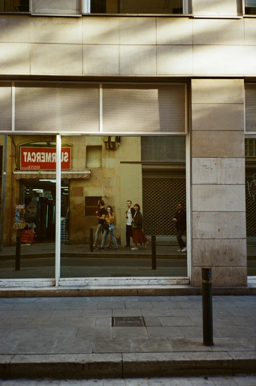 people walk in front of a store with an advertit