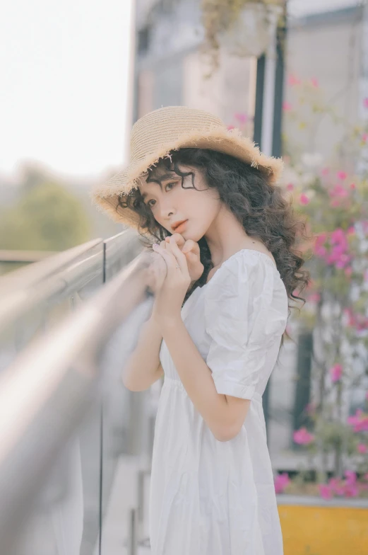 a woman in a straw hat leaning against a window