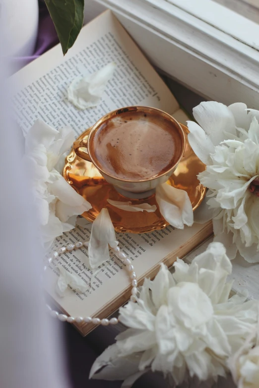 a gold cup, saucer and book surrounded by flowers