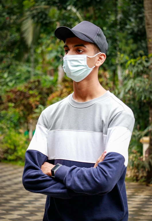 a man wearing a face mask standing with his arms crossed