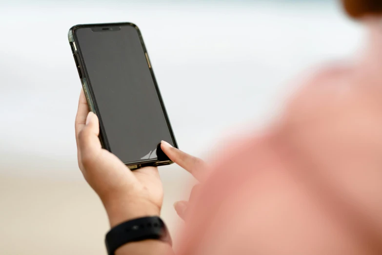 someone is holding up their smartphone on the beach