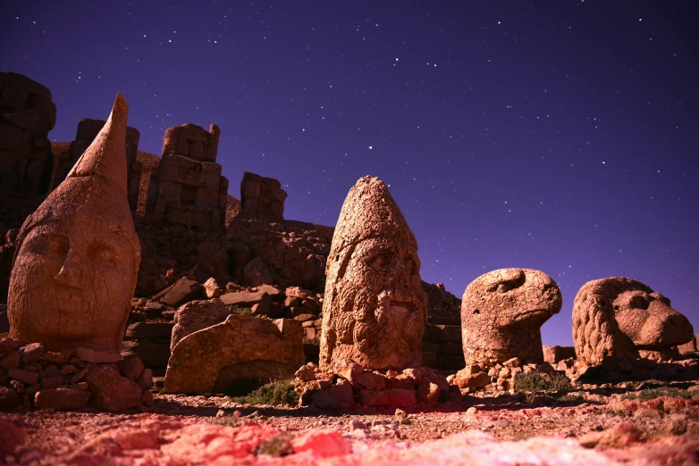 the night sky is lit up above many rocks