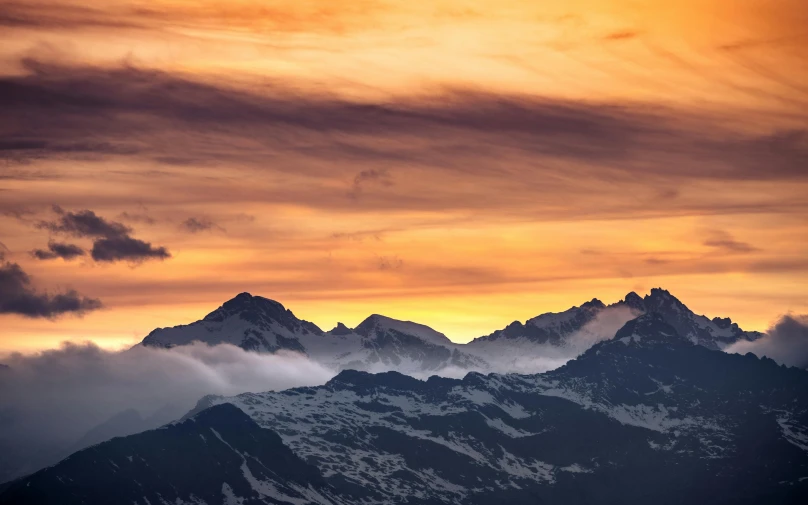 the mountains are covered in clouds at sunrise