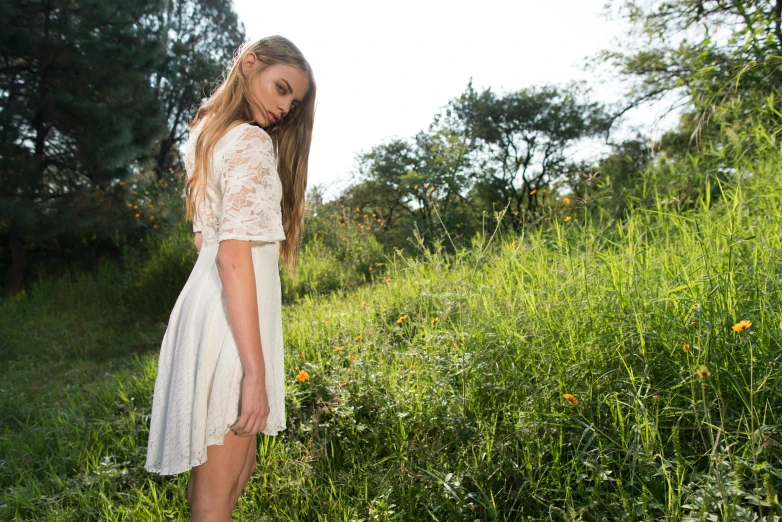 a beautiful young woman standing on top of a lush green field