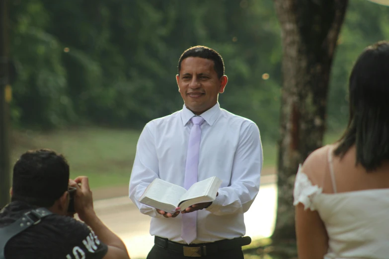 a man that is standing in the grass with a book