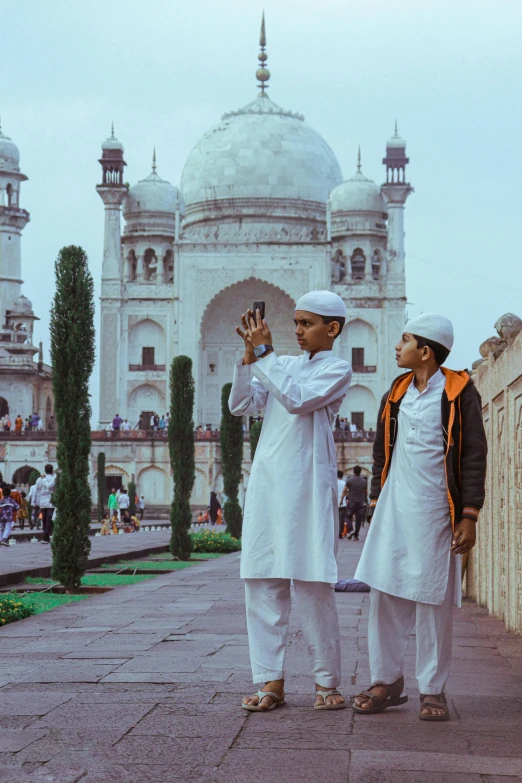 two men in white clothes standing next to each other in front of a building