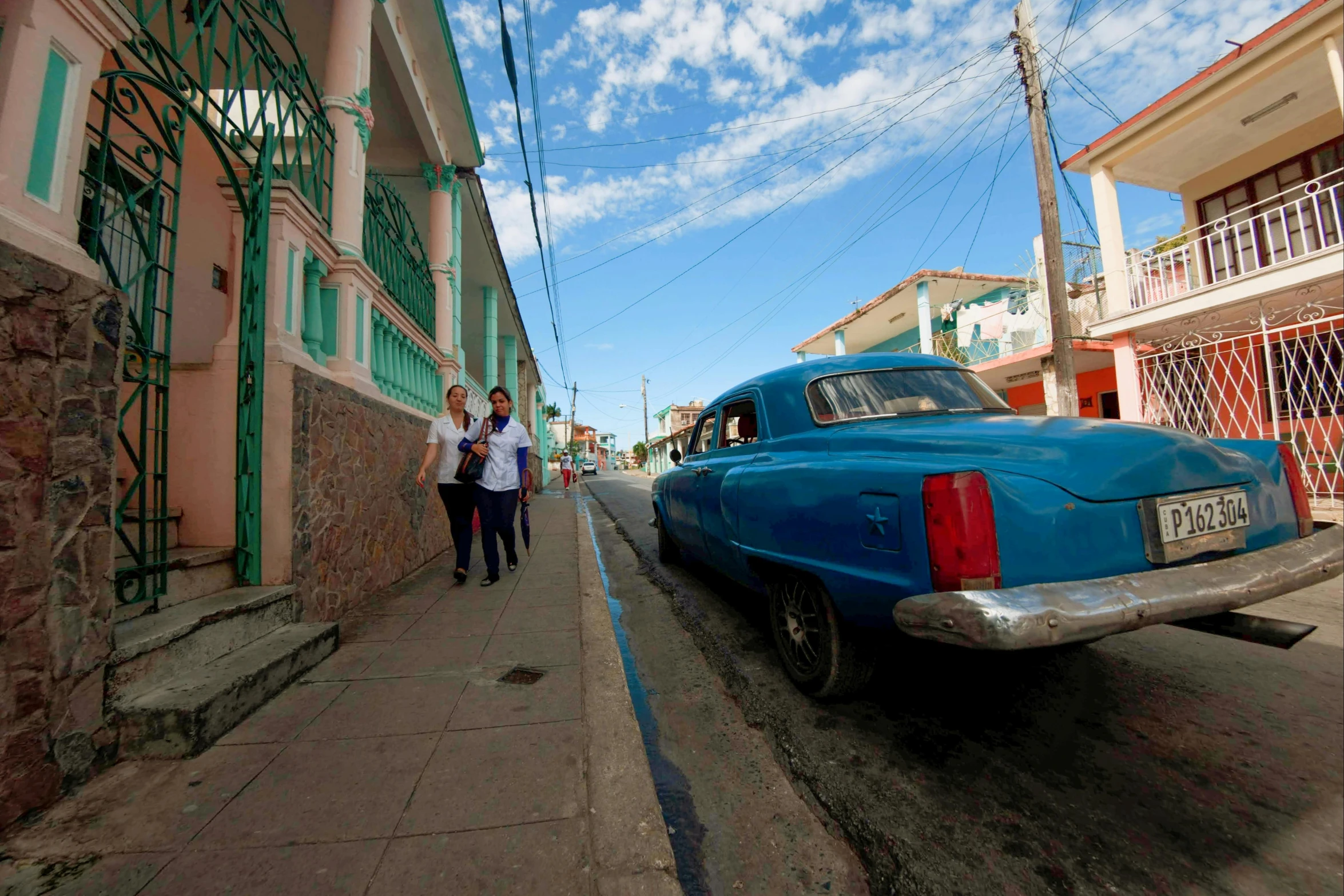 an old car and two people are on a city street