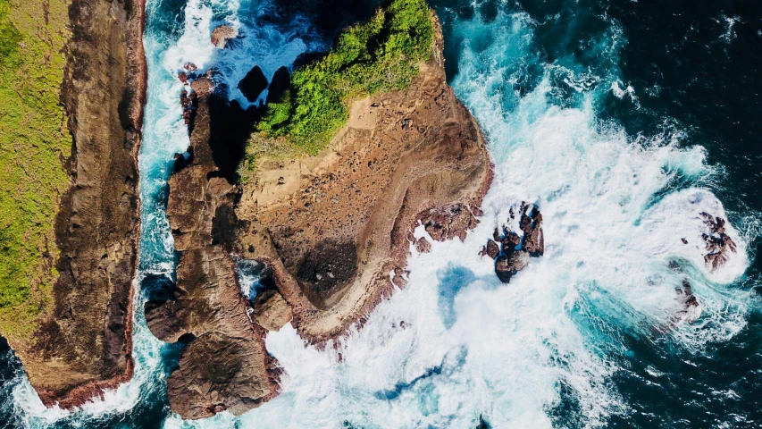 the sea, cliffs and rocks are seen from an overhead view