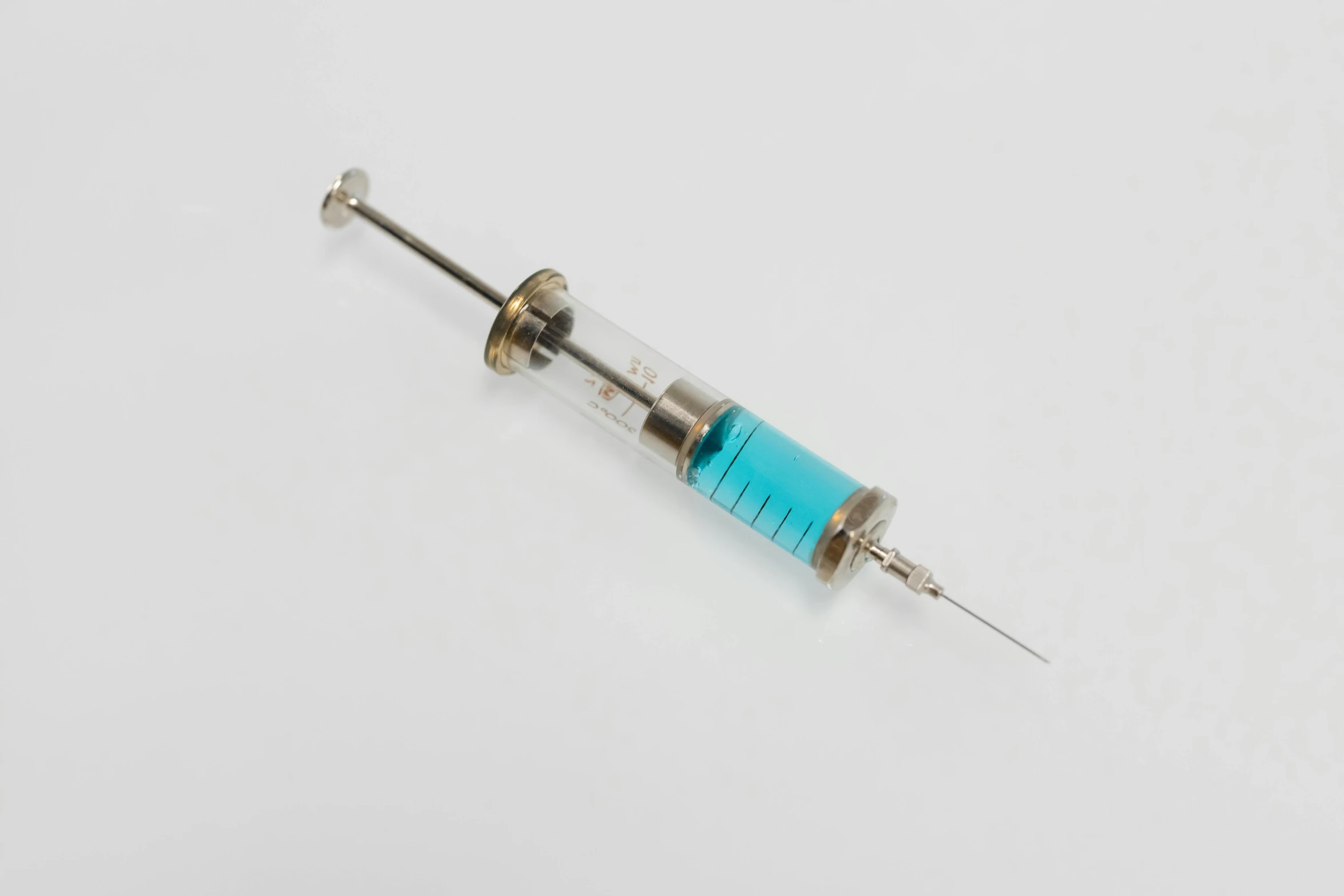 a medical needle sitting on top of an end of a blue tube