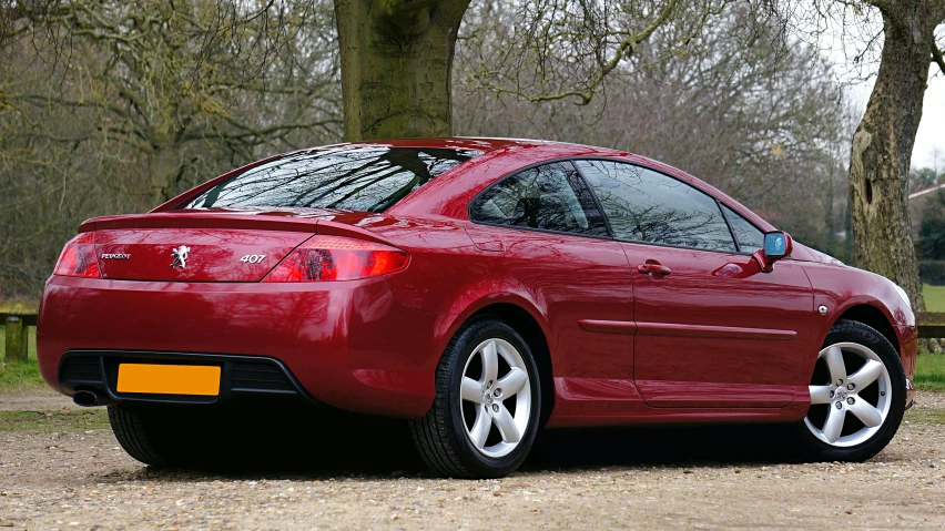 a red sports car sits parked on the gravel